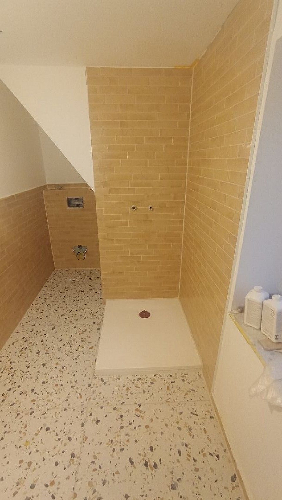 Badsanierung mit Feinsteinzeug in Terrazzo-Optik, Ziegelformat-Wandfliesen und wandbündiger Duschlösung – präzise umgesetzt und perfekt abgestimmt.